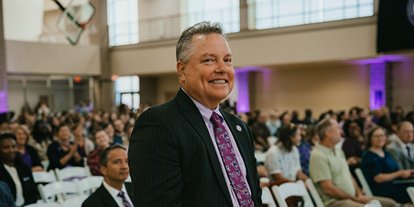 Headshot of Dr. David Jenks standing at his seat at a full event.